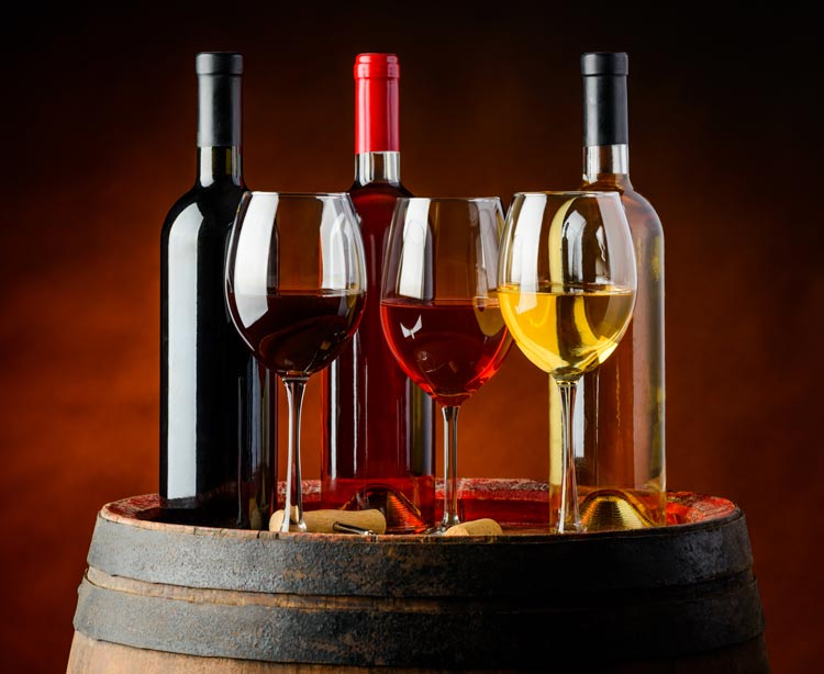 wine glasses and wine bottles on top of a wine barrel